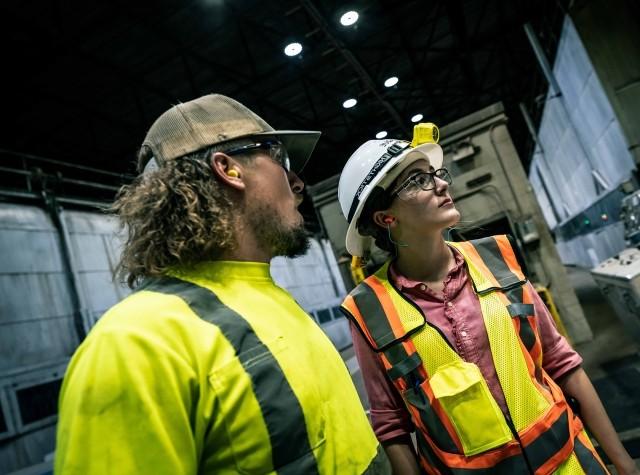 Two employees have a conversation in a paper mill